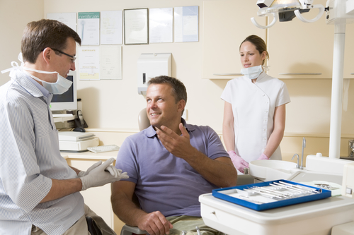 Dentist and assistant in exam room with man in chair