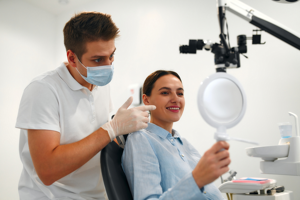patient in the dentist's chair talking to dentist smiling in mirror