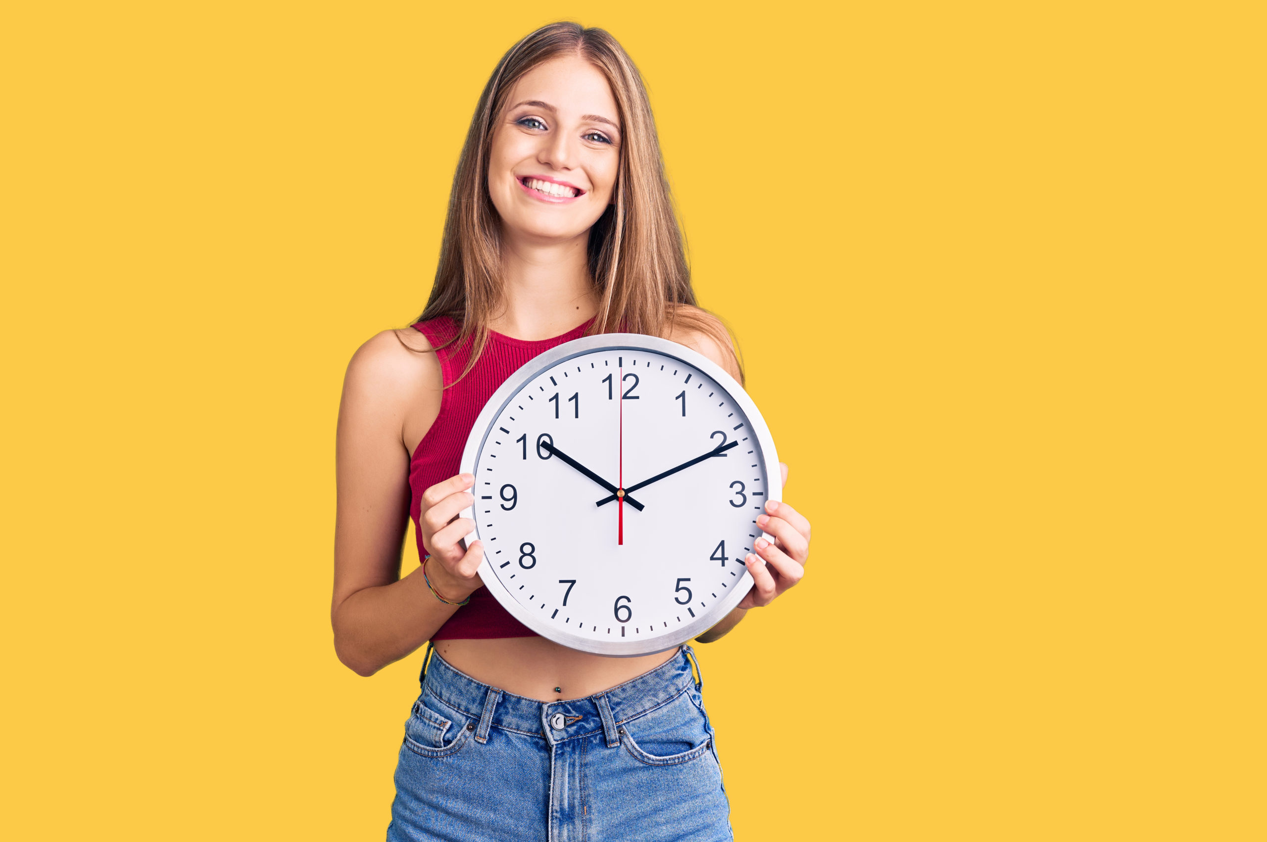 Woman smiling showing clean teeth with a clock