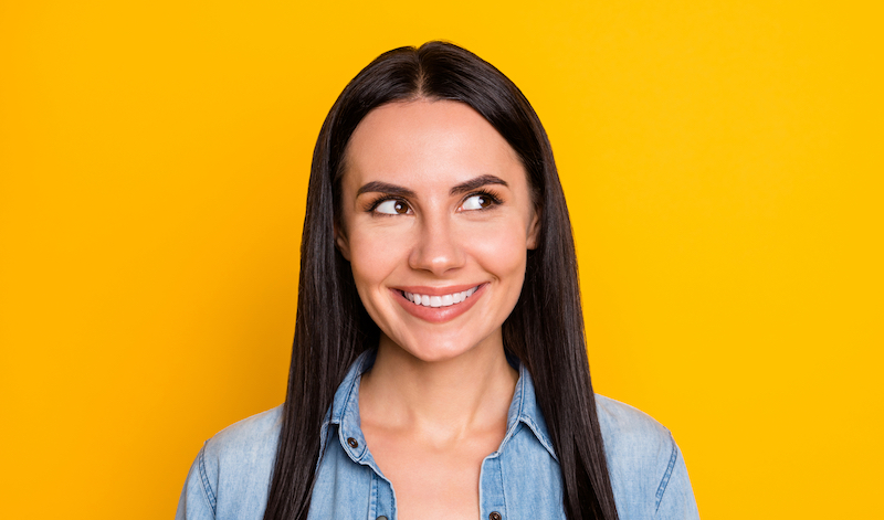 portrait of young woman smiling against yellow background