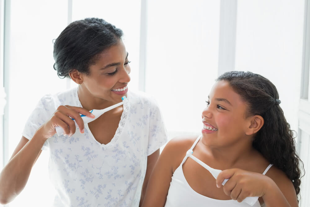 mother and child brushing teeth together
