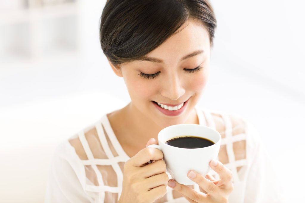 young woman with a bright smile drinking coffee in the morning