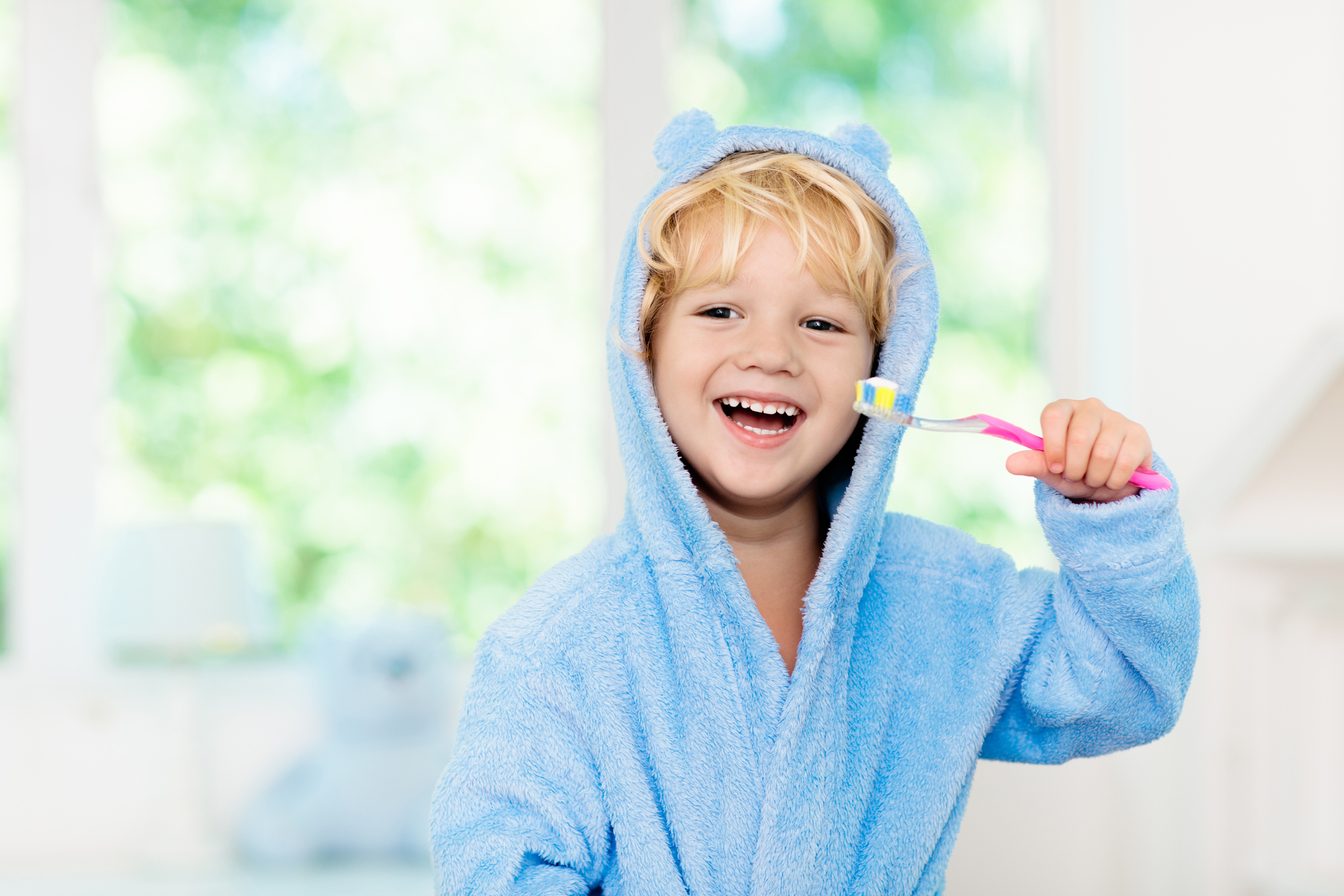 Happy toddler having fun brushing his teeth.