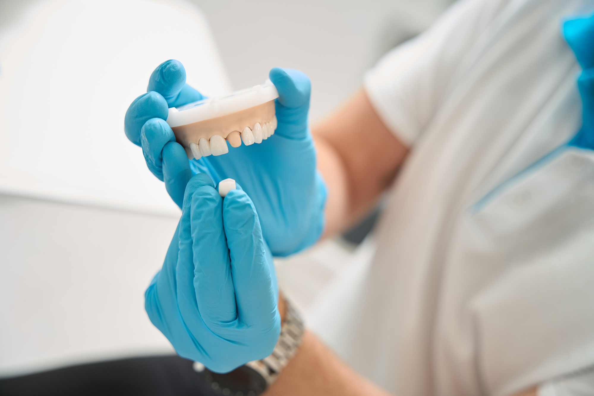 Dentist holding dental crown and maxillary teeth model