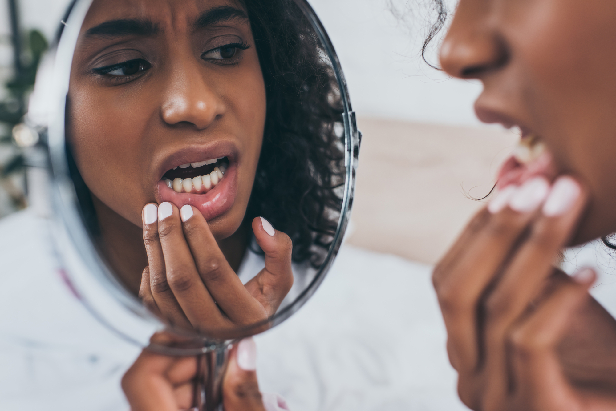 Woman looking at cracked tooth in mirror. 