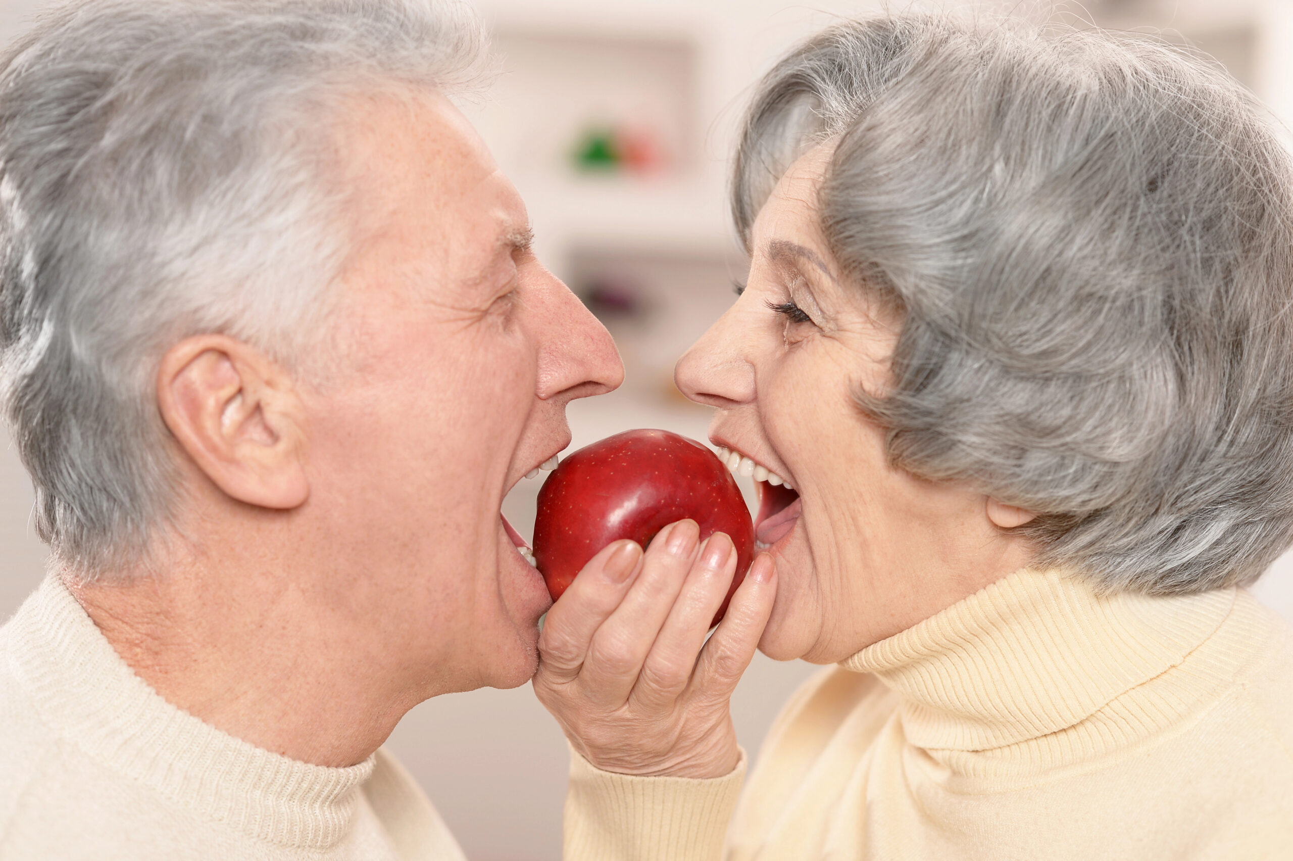 Man and Woman with dentures and dental implants eating an apple. 