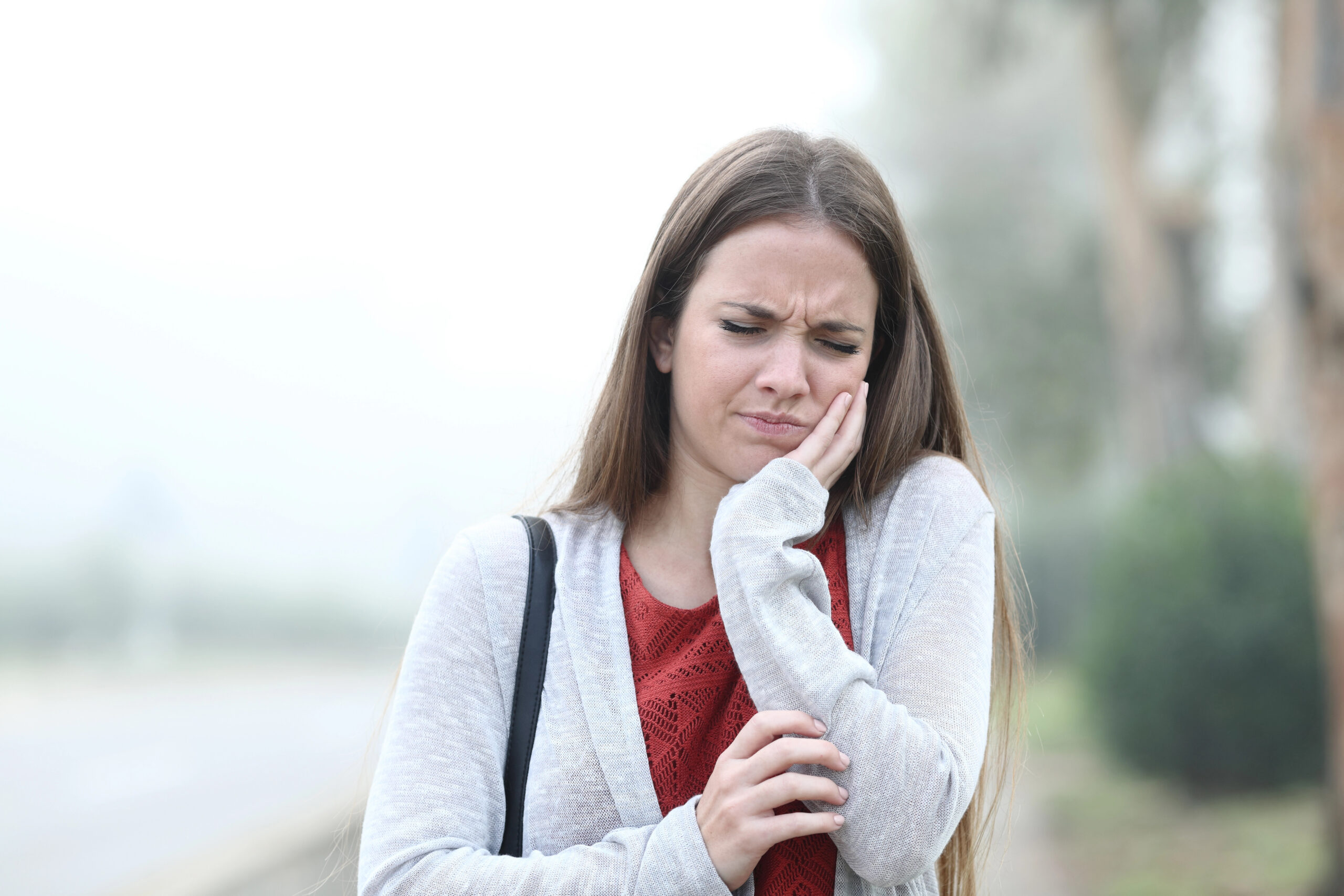 Woman outside in fall tooth pain.